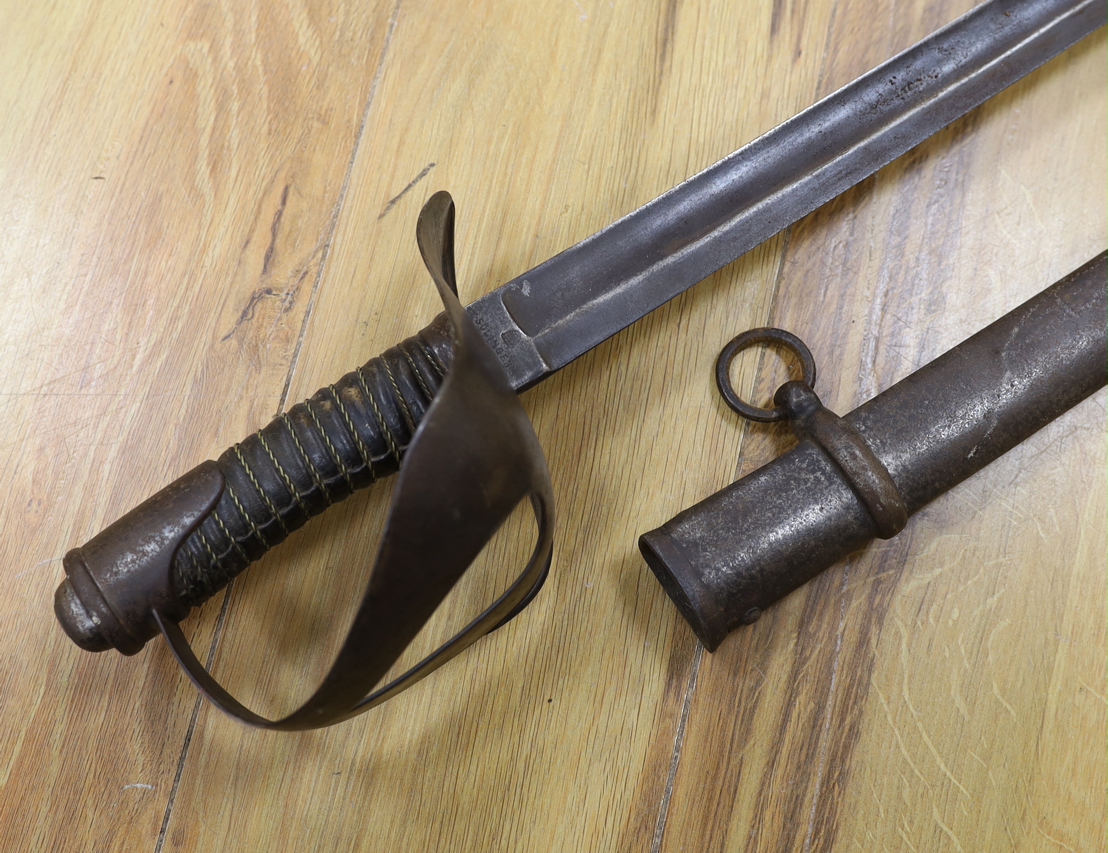 A pair of late 19th century German swords, one in its scabbard, together with another unrelated scabbard, made for the international arms trade, probably in Solingen, blade 89cm. Condition - fair, scabbards are 87cm and